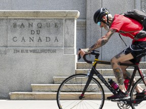 Un cycliste passe devant la Banque du Canada à Ottawa le 11 juillet 2023.