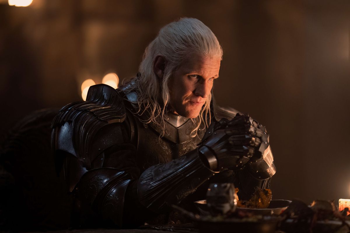 Matt Smith dans le rôle de Daemon Targaryen portant une armure et assis à une table dans la Maison du Dragon