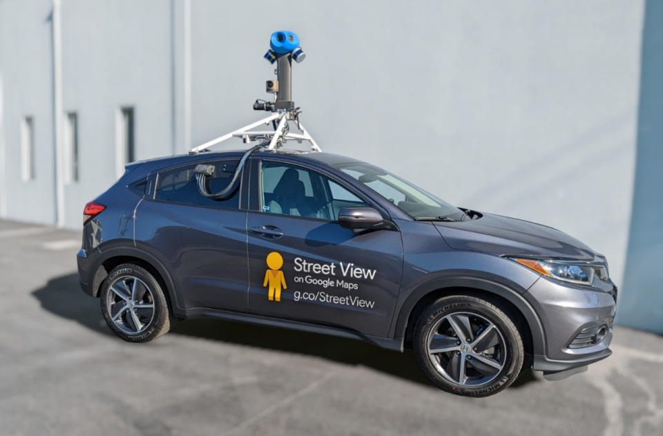 Un SUV ultra-compact équipé d’une caméra Google Street View perchée sur son toit.  Il repose sur un trottoir gris devant un mur blanc.