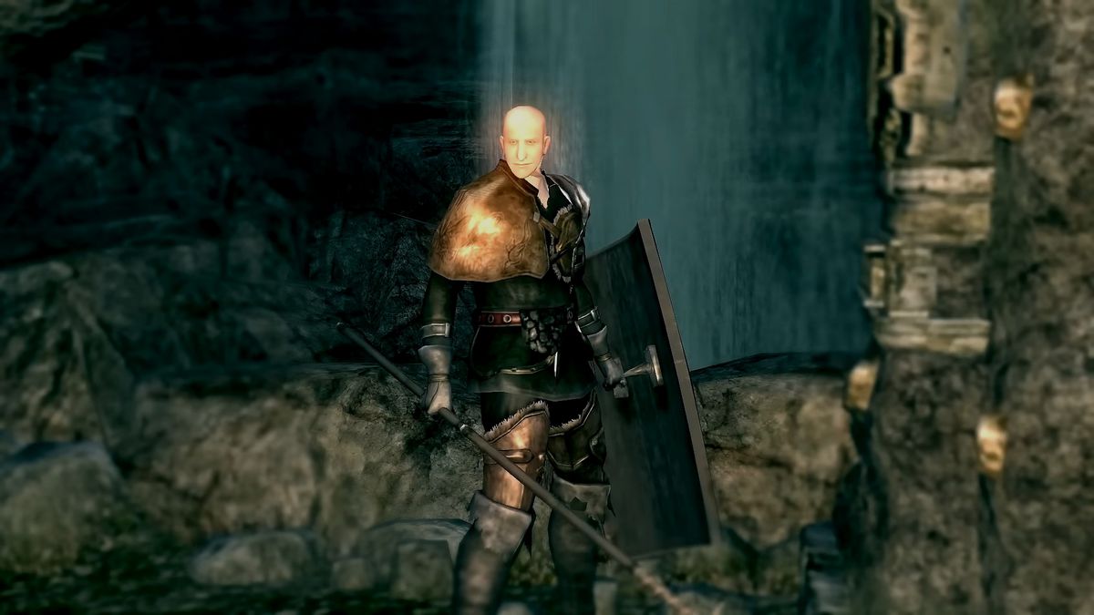 Patches se tient à côté d'un levier de pont, avec une lance et un bouclier à la main, dans une capture d'écran de Dark Souls Remastered