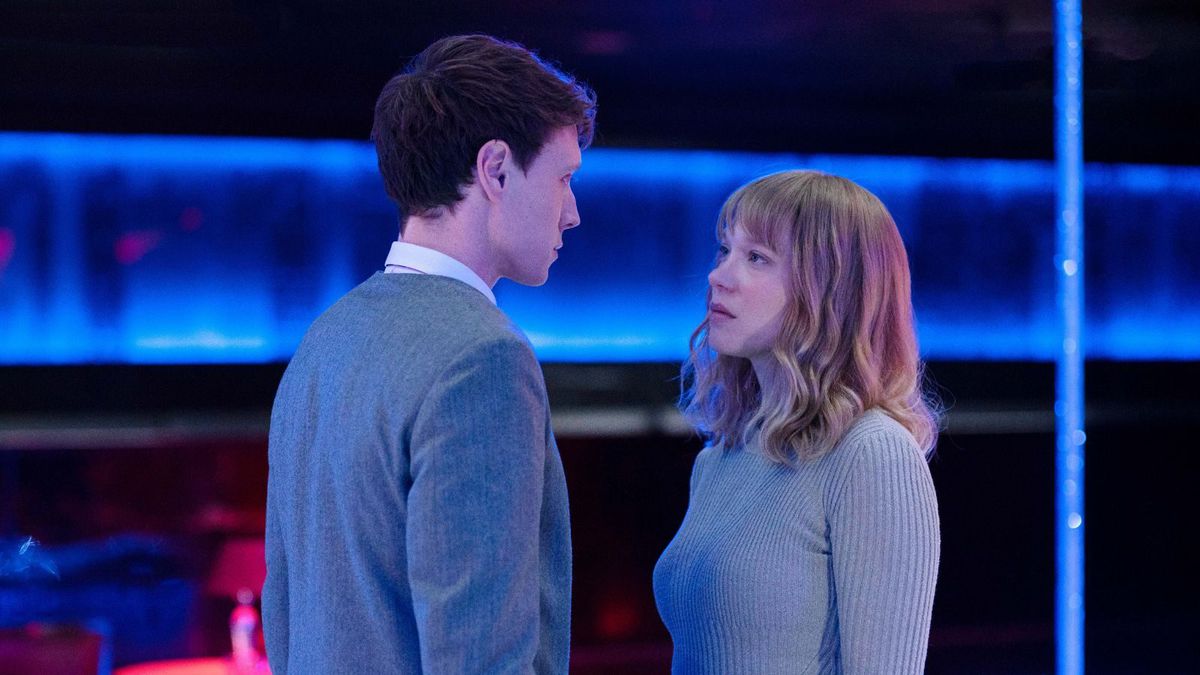 Gabrielle (Léa Seydoux) et Louis (George MacKay), un homme et une femme pâles portant des pulls bleu-gris pâle, se tiennent face à face et se regardent dans les yeux dans un espace abstrait bleu néon dans une scène de La Bête