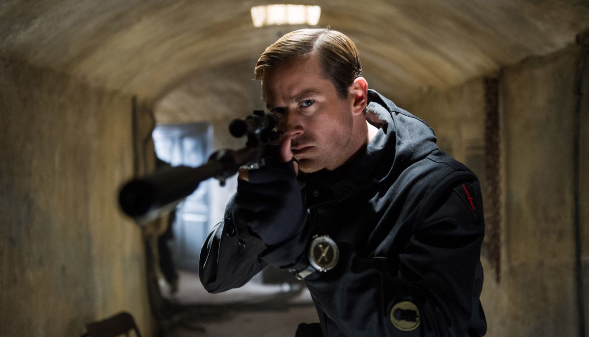 L'agent du KGB Illya Kuryakin (Armie Hammer), en noir, se tient dans un tunnel souterrain en béton et pointe un fusil de sniper vers la caméra dans The Man From UNCLE