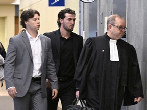 Les anciens joueurs de la Ligue junior majeure de hockey des Tigres de Victoriaville, Nicolas Daigle, à gauche, et Massimo Siciliano, ainsi que l'avocat de la défense Michel Lebrun, à droite, quittent la salle d'audience après avoir plaidé coupable, le mercredi 11 octobre 2023, à Québec.