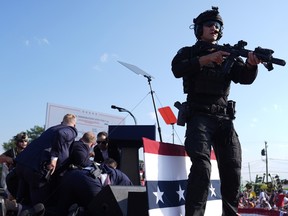 Le candidat républicain à la présidentielle, l'ancien président Donald Trump, est entouré d'agents des services secrets américains sur scène lors d'un rassemblement de campagne, le samedi 13 juillet 2024, à Butler, en Pennsylvanie.