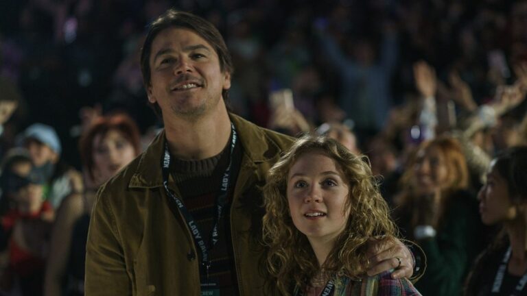 Cooper with his arm around daughter Riley in a concert crowd in M. Night Shyamalan