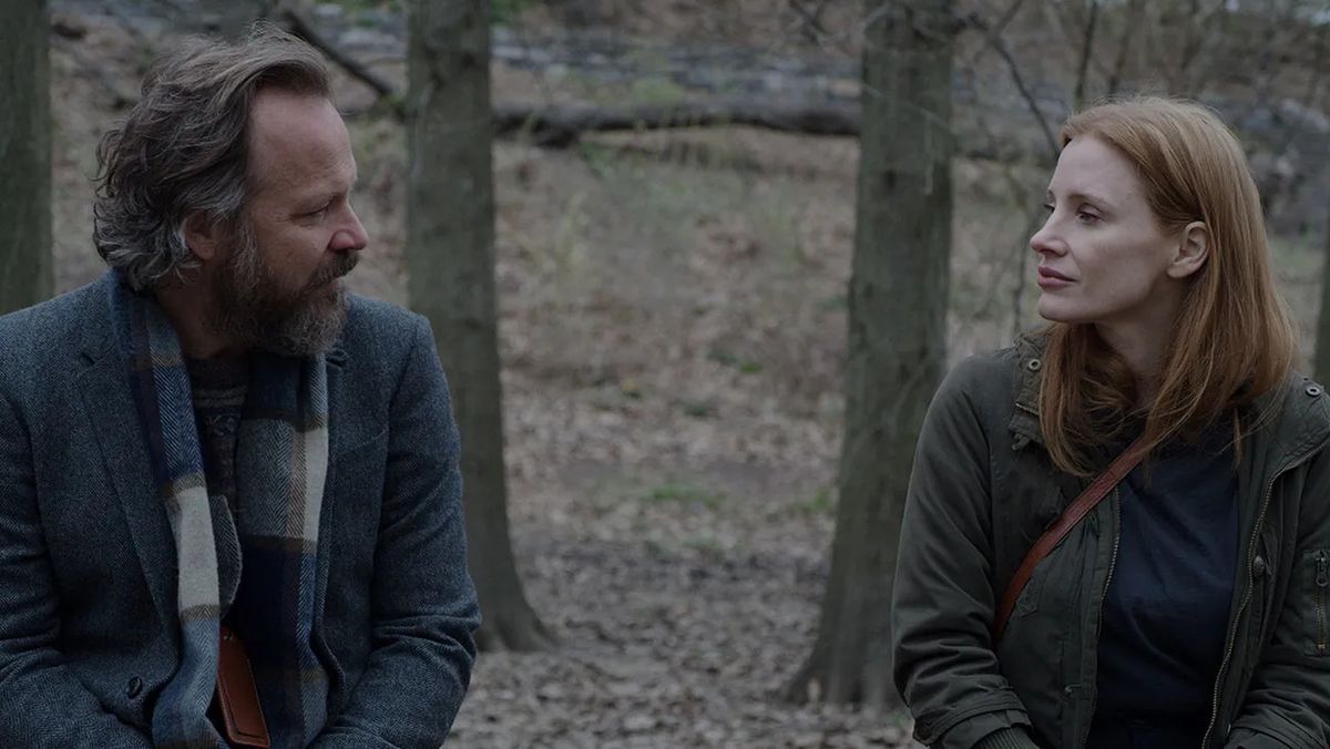 Un homme barbu et une femme aux cheveux roux sont assis l'un à côté de l'autre dans une forêt.