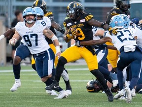 Le porteur de ballon des Hamilton Tiger Cats, James Butler (9), perce la ligne défensive des Argonauts de Toronto lors d'un match de football de la LCF à Hamilton, en Ontario, le samedi 20 juillet 2024.