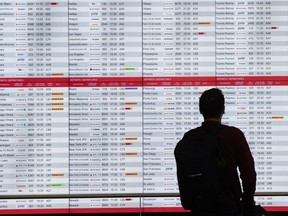 Un passager vérifie les heures de départ à l'aéroport international Trudeau le vendredi 19 juillet 2024 à Montréal.