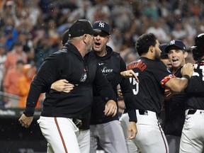 Le manager des Yankees de New York, Aaron Boone, au centre, et le manager des Orioles de Baltimore, Brandon Hyde, à gauche, se disputent après que les joueurs ont quitté les bancs pendant la neuvième manche d'un match de baseball, le vendredi 12 juillet 2024, à Baltimore.