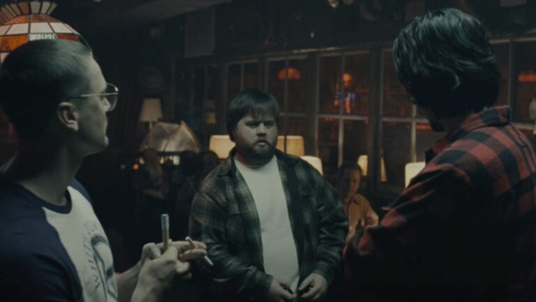 Paul Walter Hauser stands in the middle of a group of guys playing pool in BlacKkKlansman.