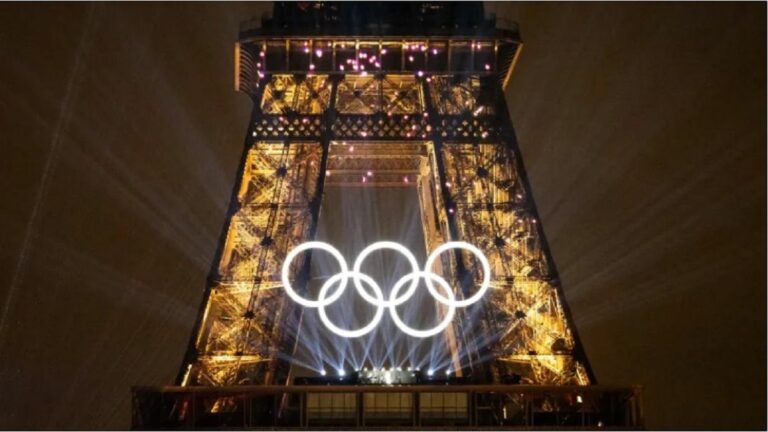 The five Olympic rings in front of the Eiffel Tower at night