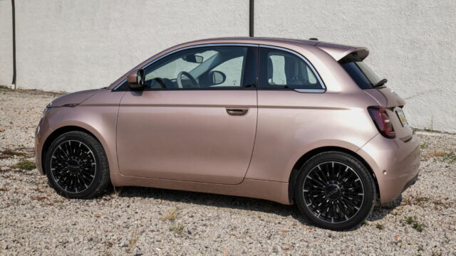 Une voiture en or rose se démarque dans une mer de SUV monochromes.