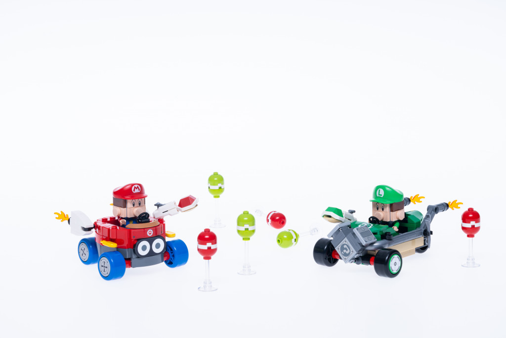 Images promotionnelles officielles pour l'ensemble de kart standard LEGO Mario Kart. On y voit un bébé Mario et un bébé Luigi construits en briques LEGO conduisant différents karts personnalisés. Le bébé Luigi semble lancer une carapace verte, tandis que Bébé Mario est sur le point de lancer une carapace rouge. Ils sont entourés de ballons construits en Lego.