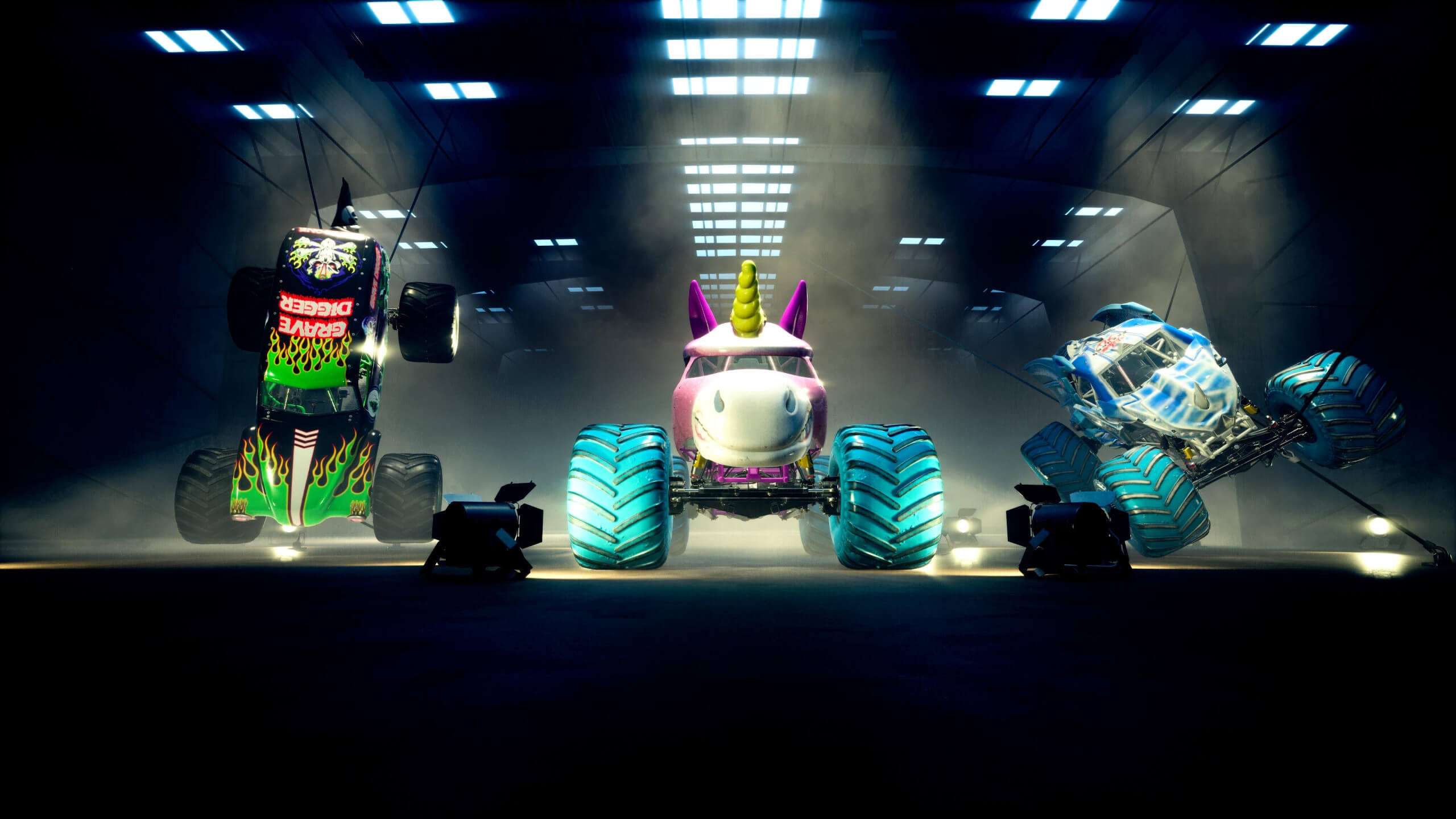 capture d'écran de Monster Jam Showdown : Une image du garage avec trois camions exposés, Grave Digger, Sparkly Smash et Bakugan Dragonoid.