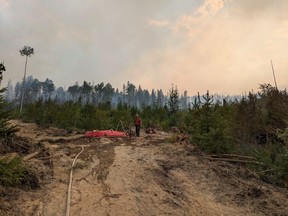 Un pompier forestier des BC Wildfire Services s'occupe d'une pompe sur le terrain de l'incendie de forêt de Dogtooth, près de Golden, en Colombie-Britannique, sur une photo distribuée le 28 juillet 2024.