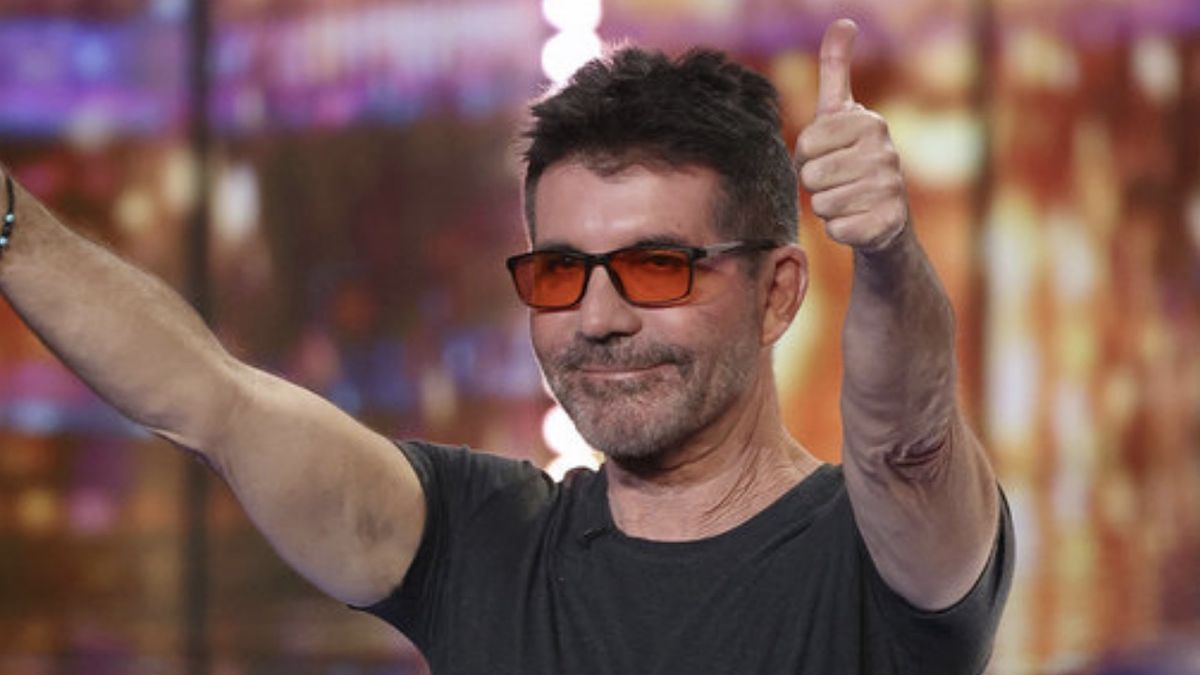 Simon Cowell in orange-tinted glasses giving the crowd two thumbs up on America