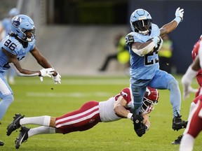 Le porteur de ballon des Argonauts Ka'Deem Carey (25) évite un plaquage du demi défensif des Stampeders Bailey Devine-Scott (21) lors de la première mi-temps de la LCF à Toronto, le vendredi 9 août 2024.