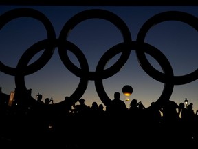 Les gens regardent le chaudron s'élever au coucher du soleil près des anneaux olympiques lors des Jeux olympiques d'été de 2024, le lundi 5 août 2024, à Paris, en France.