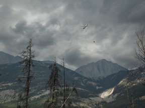 Un hélicoptère déverse de l'eau sur des incendies qui couvent à l'extérieur de Jasper, en Alberta, le vendredi 26 juillet 2024.