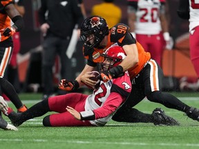 Le quart-arrière des Stampeders de Calgary Jake Maier (12) est plaqué par Mathieu Betts (90) des Lions de la Colombie-Britannique alors qu'il glisse sur le sol pendant la première mi-temps d'un match de football de la LCF à Vancouver, le 24 septembre 2022. Le joueur de ligne défensive vedette Mathieu Betts retourne chez les Lions de la Colombie-Britannique en difficulté.