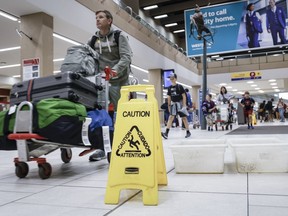 Les voyageurs manœuvrent autour des seaux pour récupérer les fuites alors que des réparations sont en cours à l'aéroport international de Calgary après que certaines parties de son terminal intérieur ont été fermées tard lundi en raison de dommages causés par la grêle et de fortes pluies, à Calgary, mardi 6 août 2024.