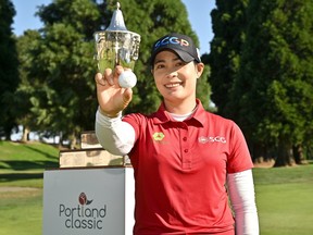 Moriya Jutanugarn de Thaïlande pose avec un trophée et sa balle de golf.