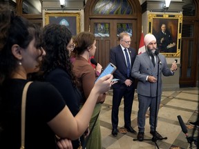 Le député du NPD Peter Julian regarde le chef Jagmeet Singh parler aux journalistes dans le foyer de la Chambre des communes, le jeudi 19 septembre 2024 à Ottawa.