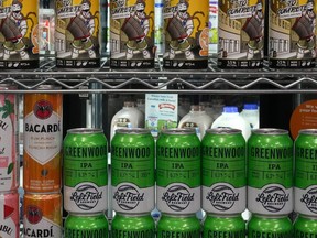 Des canettes de bière sont empilées devant un étalage de lait dans un dépanneur à Toronto, le jeudi 14 décembre 2023.