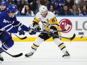 Sidney Crosby (87) des Penguins de Pittsburgh passe tandis que Morgan Rielly (44) des Maple Leafs de Toronto défend lors de la troisième période de hockey de la LNH à Toronto, le lundi 8 avril 2024.