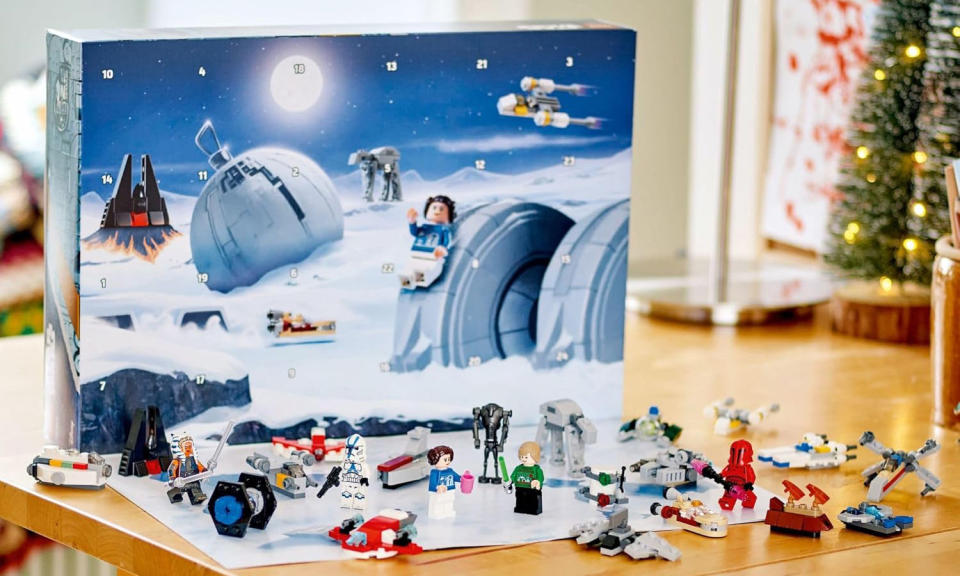 Le calendrier de l'Avent Lego Star Wars est disposé sur une table avec un sapin de Noël en arrière-plan. 