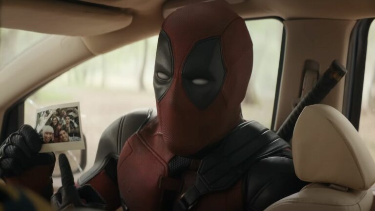 Close-up of Deadpool pointing to Polaroid picture of all of his friends in Deadpool &amp; Wolverine