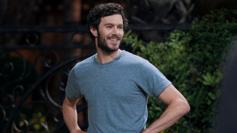 Adam Brody smiling with his hands on his hips in Nobody Wants This.