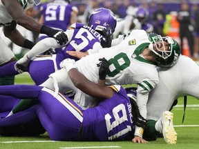 Le quart-arrière des Jets de New York Aaron Rodgers, à droite, réagit alors qu'il est plaqué lors de la seconde moitié d'un match de football de la NFL contre les Vikings du Minnesota, le dimanche 6 octobre 2024, au stade Tottenham Hotspur à Londres.